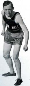 Black and white image of alumnus Melvin Dalton in his Seton Hall track uniform, in a stance so he appears ready to run