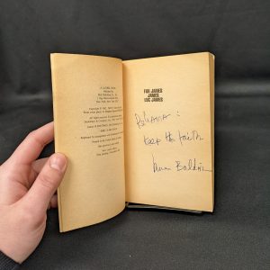 An open book with Baldwin's inscription visible on a black background