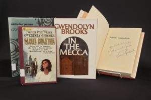 Four books, one open, displaying Brooks' signature