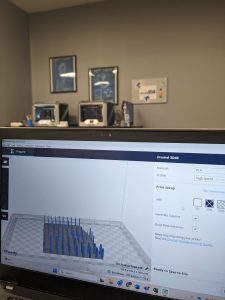 Computer screen shows DigiLab Slicer program with3D printers in the background of the photo