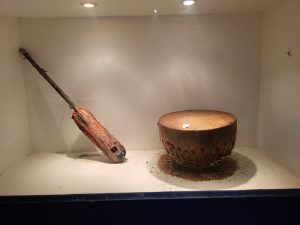 Two ancient musical instruments sit in a museum display case. 