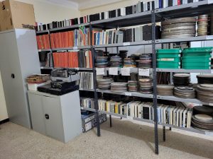 Shelves hold a variety of obsolete audio video formats, from audio tape to cassettes to VHS recordings.