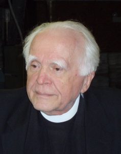 Catholic priest with white hair and bushy eyebrows