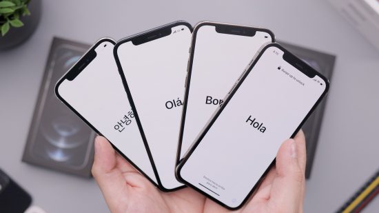 A bunch of phones spread out in a person's hand. Each phone screen having a different language of saying hello. 
