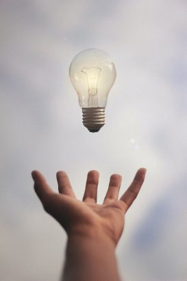 Light bulb hovering over hand 