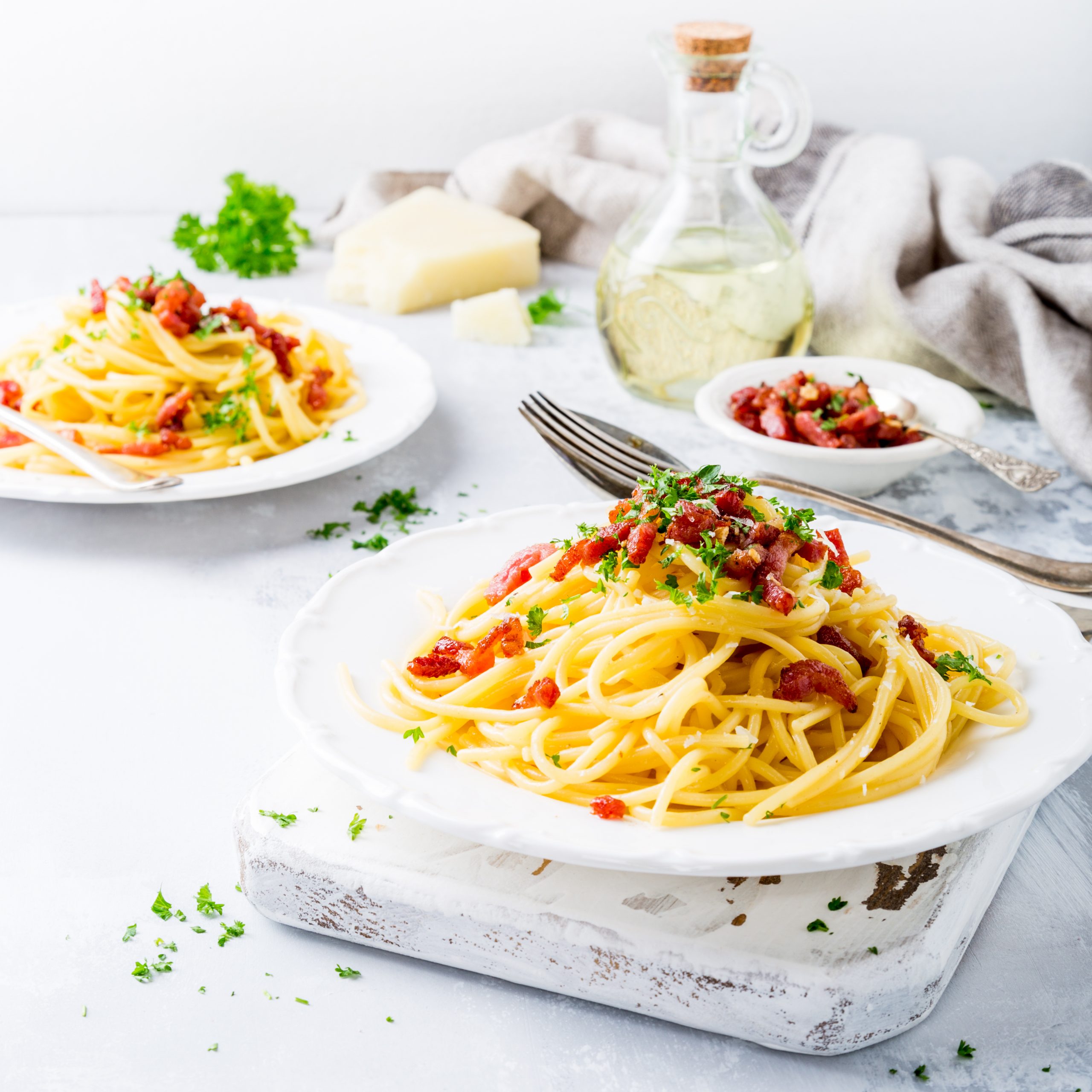 Italian pasta spaghetti Carbonara with fried bacon, parmesan cheese and parsley on white plate.