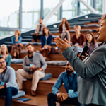 Woman of color engaged in public speaking at a business conference at convention center