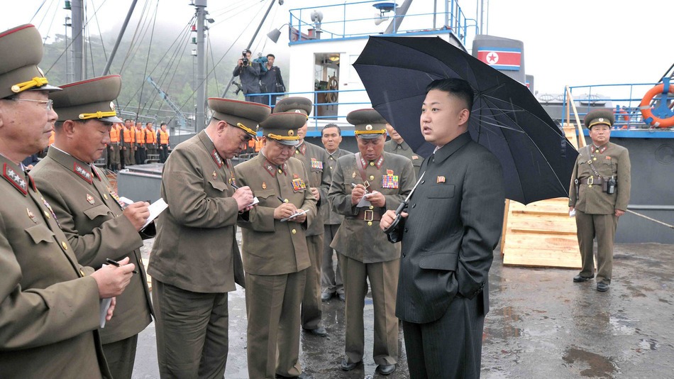 Kim Jong Un communicating with several members of the military.  