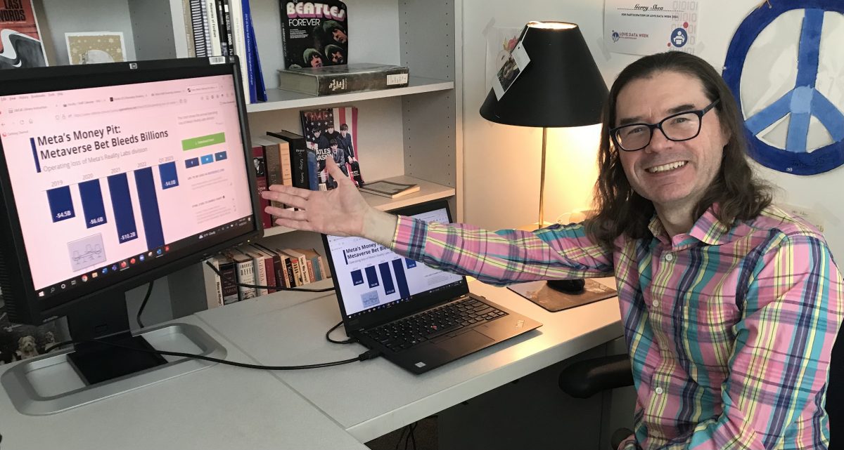 Photo of librarian Gerry Shea pointing at bar graph about Meta on his computer screen