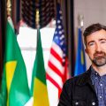 joseph huddleston standing in front of flags