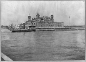 This is the view of Ellis Island from the water that immigrants saw before entering into their new home, America. In this image we can see the docking station of smaller boats that took immigrants from the large vessels to the island. Circa 1913
